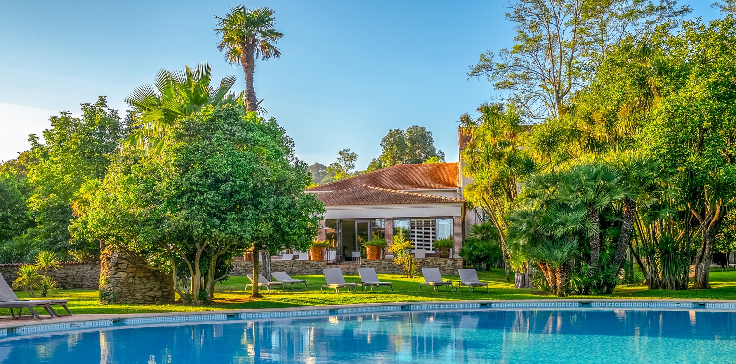 Jardin verdoyant avec piscine et chaises longues. Château Valmer- Agence-web-hotel